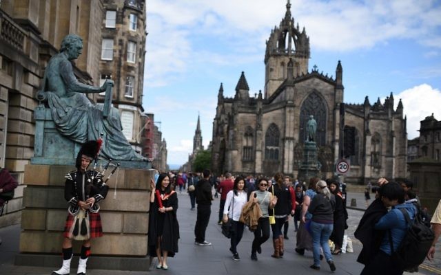 Un artiste de rue joue de la cornemuse près d'une statue du philosophe écossais David Hume, à Édibourg, en Ecosse, le 25 juin 2015. Illustration. (Crédit : Oli Scarff/AFP)