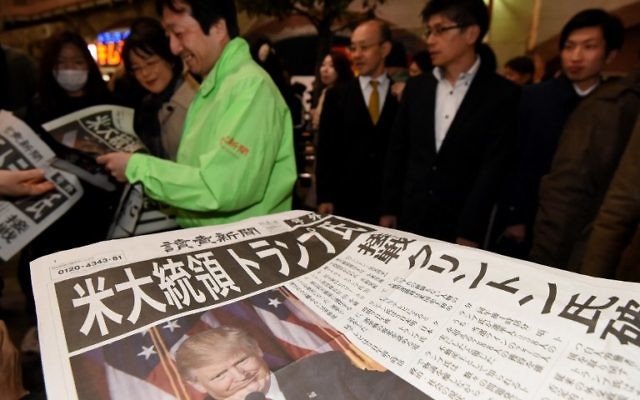 Un homme distribue des éditions supplémentaires des journaux annonçant la victoire de Donald Trump à l'élection présidentielle américaine à Tokyo, le 9 novembre 2016. (Crédit : AFP/Toru Yamanaka)