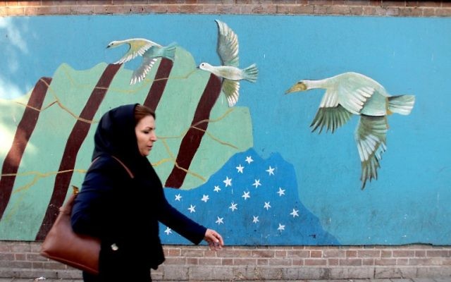 Une Iranienne voilée devant une fresque dessinée su le mur de l'ancienne ambassade américaine à Téhéran, le 9 novembre 2016. (Crédit : Atta Kenare/AFP) Une Iranienne voilée devant une fresque dessinée su le mur de l'ancienne ambassade américaine à Téhéran, le 9 novembre 2016. (Crédit : Atta Kenare/AFP)