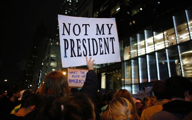 Un homme portant une affiche alors qu'il participe à une manifestation contre le président élu Donald Trump à New York le 9 novembre 2016 (Crédit : KENA BETANCUR / AFP)