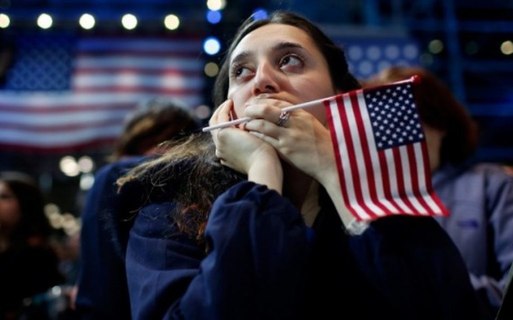 Une femme tient un drapeau américain alors qu'elle regarde les résultats du vote à l'élection présidentielle au Jacob K. Javits Convention Center à New York le 9 novembre 2016. (Crédit : Win McNamee / Getty Images / AFP) Une femme tient un drapeau américain alors qu'elle regarde les résultats du vote à l'élection présidentielle au Jacob K. Javits Convention Center à New York le 9 novembre 2016. (Crédit : Win McNamee / Getty Images / AFP)