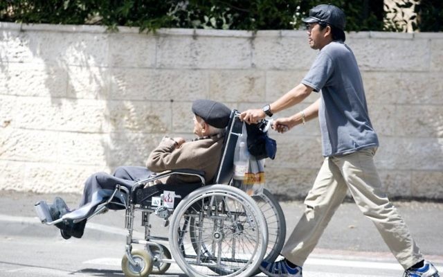 Un aide domestique philippin pousse un Israélien âgé en chaise roulante, le 22 avril 2009. Illustration. (Crédit : Abir Sultan/Flash90)