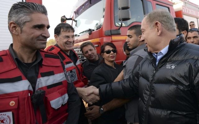 Le Premier ministre Benjamin Netanyahu avec les pompiers israéliens pendant sa visite au centre de commandement des incendies de Zichron Yaakov, le 23 novembre 2016. (Crédit : Haim Zach/GPO)