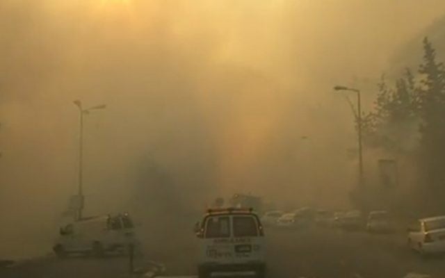 Une ambulance se frayant son chemin à travers les rues enfumées de Haïfa, le 24 novembre 2016. (Crédit : capture d'écran Dixième chaîne)