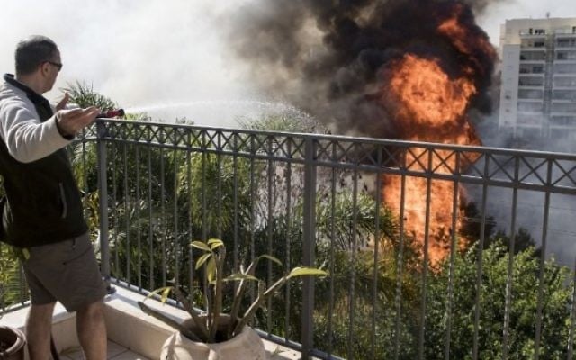 Un Israélien essaie d'éteindre un incendie d'un toit dans la ville d'Haïfa, le 24 novembre 2016 (Crédit : AFP PHOTO / JACK GUEZ)
