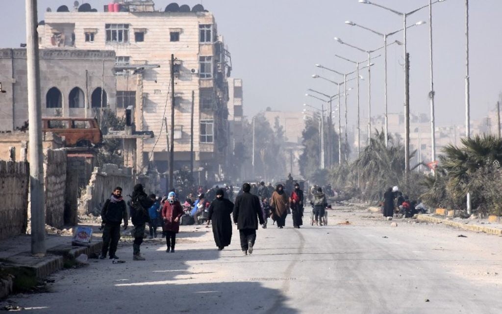 Les civils syriens marchant vers un poste de contrôle tenu par les forces pro-gouvernementales, au rond-point de la rue Al-Hawoz, après avoir quitté les quartiers de l'est d'Alep le 10 décembre 2016 (Crédit : George Ourfalian/AFP)