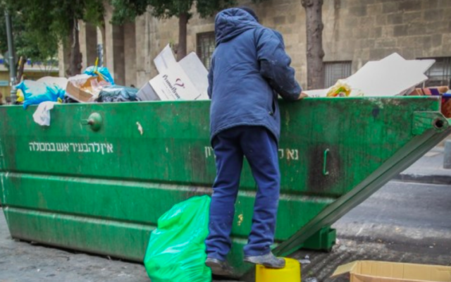 Photo d'illustration d'un homme cherchant de la nourriture dans une poubelle (Crédit : Flash 90) Photo d'illustration d'un homme cherchant de la nourriture dans une poubelle (Crédit : Flash 90)