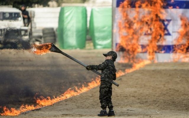 Un petit garçon palestinien enflamme un drapeau israélien pendant la cérémonie de fin d'un programme de formation militaire du Hamas, à Gaza Ville, le 22 janvier 2017. (Crédit : Mahmud Hams/AFP)