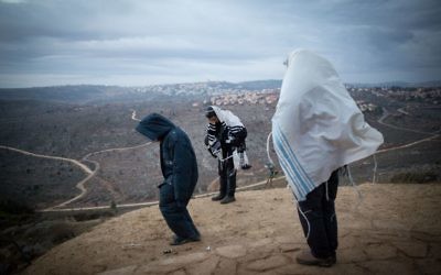 Des Juifs priant tôt le matin sur la colline surplombant Ofra, dans l'avant-poste d'Amona en Cisjordanie, le 18 décembre 2016. (Crédit : Miriam Alster/Flash90)