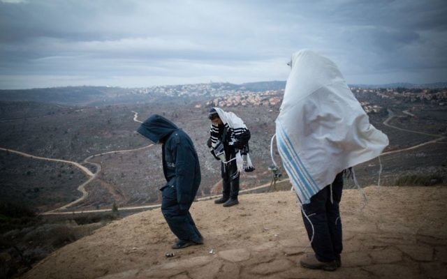 Des Juifs priant tôt le matin sur la colline surplombant Ofra, dans l'avant-poste d'Amona en Cisjordanie, le 18 décembre 2016. (Crédit : Miriam Alster/Flash90)