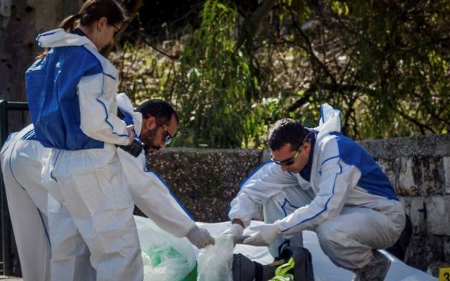 Des médecins légistes enquêtent sur le lieu où un homme a été assassiné après qu'un tireur inconnu ait ouvert le feu, faisant un mort, à Haifa, le 3 janvier 2017 (Crédit : Meir Vaknin/Flash90)