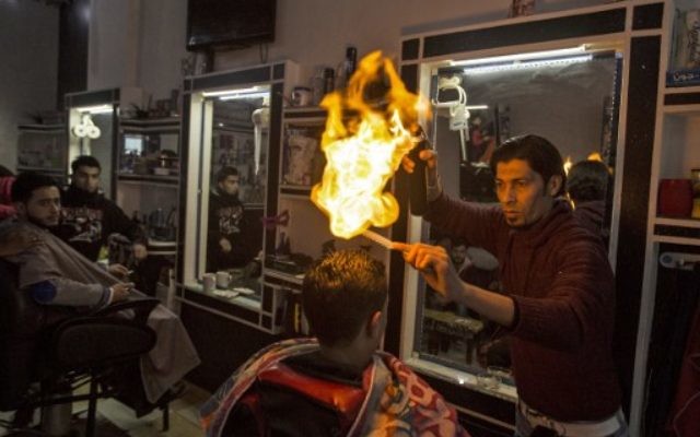 Ramadan Edwan, un coiffeur palestinien, utilise le feu pour coiffer ses clients, dans le camp de réfugiés de Rafah, dans le sud de la bande de Gaza, le 1er février 2017. (Crédit : Mahmud Hams/AFP) Ramadan Edwan, un coiffeur palestinien, utilise le feu pour coiffer ses clients, dans le camp de réfugiés de Rafah, dans le sud de la bande de Gaza, le 1er février 2017. (Crédit : Mahmud Hams/AFP)