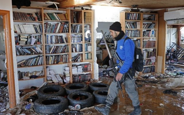 Un policier marchant à l'intérieur de la synagogue d'Amona où les jeunes se sont barricadés avant d'être expulsés le 2 février 2017 (Crédit : AFP PHOTO / Thomas COEX)