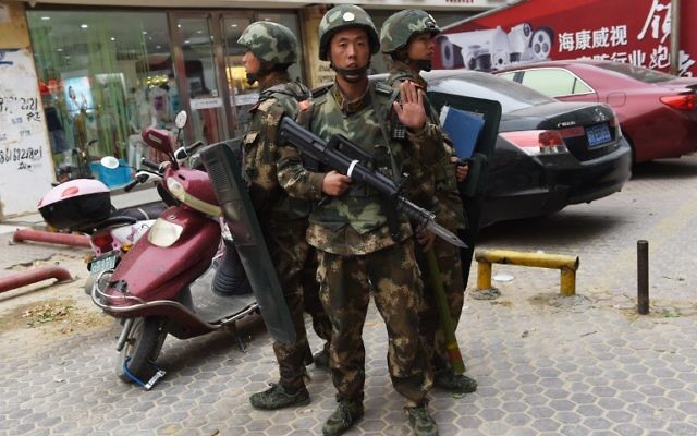 Policiers des forces spéciales déployés devant le centre commercial de Hotan, dans la région chinoise de Xinjiang, en proie à des tensions entre les Hans et les Ouïghours musulmans, dans le cadre de la campagne "anti-terroriste", le 16 avril 2015. (Crédit : Greg Baker/AFP)