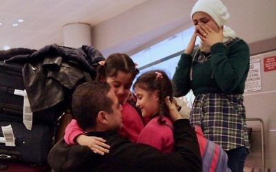 Fadi Kassar embrasse ses deux petites filles, qu'il n'a pas vu depuis deux ans, après avoir retrouvé sa famille à l'aéroport JFK de New York, le 2 février 2017. (Crédit : Bill Swersey/HIAS)