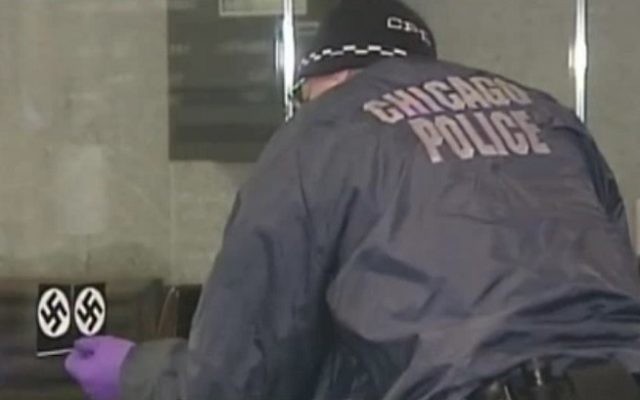 Un agent de police enlève un autocollant représentant une croix gammée sur la porte de la synagogue Loop de Chicago le 4 février 2017. La police estime qu'il s'agit d'un crime de haine. (Capture d'écran : NBC Chicago) Un agent de police enlève un autocollant représentant une croix gammée sur la porte de la synagogue Loop de Chicago le 4 février 2017. La police estime qu'il s'agit d'un crime de haine. (Capture d'écran : NBC Chicago)