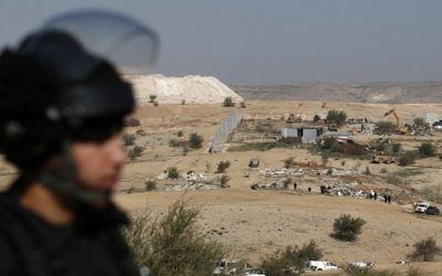 Un policier israélien en train de protéger les bulldozers qui détruisent des maisons dans le village bédouin d'Umm al-Hiran, dans le désert du Néguev, le 18 janvier 2017. (Crédit : Menahem Kahana/AFP)