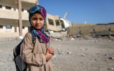 Une fillette yéménite devant une école détruite par une frappe aérienne dans la ville de Taëz, dans le sud du Yémen, le 16 mars 2017. (Crédit : Ahmad Al-Basha/AFP)
