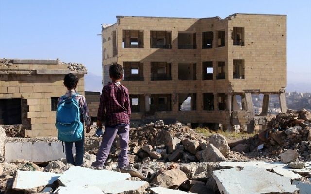 Des enfants yéménites devant une école détruite par une frappe aérienne dans la ville de Taëz, dans le sud du Yémen, le 16 mars 2017. (Crédit : Ahmad Al-Basha/AFP)