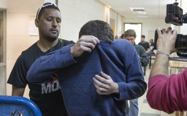 L'adolescent juif israélo-américain, au centre, qui a été accusé d'avoir fait des dizaines d'alertes à la bombe antisémites aux Etats-Unis et ailleurs, escorté par des gardes alors qu'il quitte le tribunal de Rishon Lezion, le 23 mars 2017. (Crédit : Jack Guez/AFP) L'adolescent juif israélo-américain, au centre, qui a été accusé d'avoir fait des dizaines d'alertes à la bombe antisémites aux Etats-Unis et ailleurs, escorté par des gardes alors qu'il quitte le tribunal de Rishon Lezion, le 23 mars 2017. (Crédit : Jack Guez/AFP)