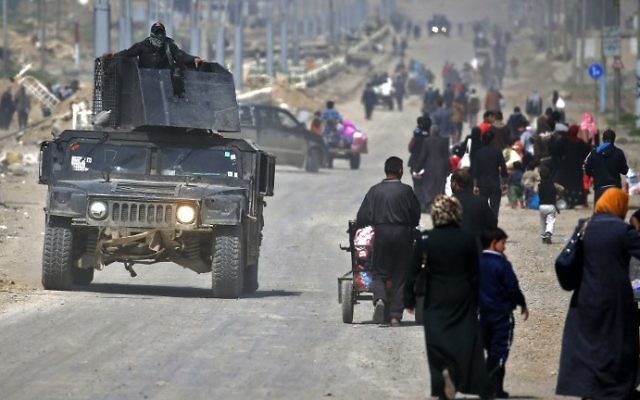 Les forces de sécurité irakiennes passent devant des civils qui fuient la vieille ville de Mossoul, en raison des combats entre les forces gouvernementales et l'Etat islamique, le 30 mars 2017. (Crédit : Ahmad Gharabli/AFP) Les forces de sécurité irakiennes passent devant des civils qui fuient la vieille ville de Mossoul, en raison des combats entre les forces gouvernementales et l'Etat islamique, le 30 mars 2017. (Crédit : Ahmad Gharabli/AFP)