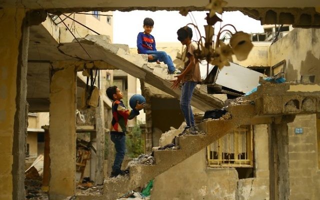 Des enfants palestiniens dans les ruines d'un immeuble détruit pendant la guerre de 2014, à Gaza Ville, le 13 avril 2017. (Crédit : Mohammed Abed/AFP)