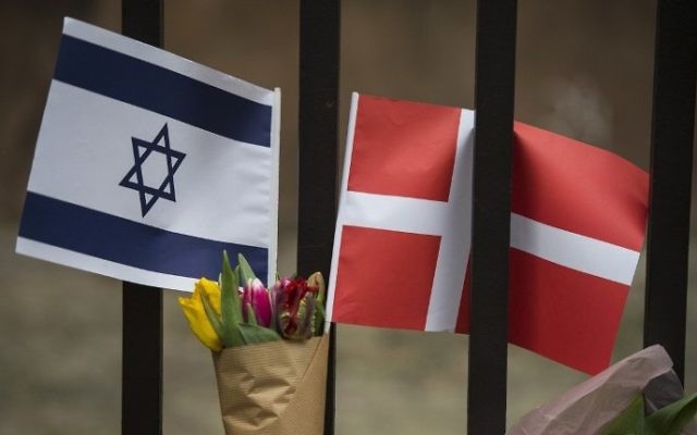 Un drapeau danois et israélien vu parmi les fleurs et les bougies déposés en honneur aux victimes d'une attaque à l'extérieur de la synagogue principale à Copenhague, au Danemark, le 15 février 2015 (Crédit : AFP / Odd Andersen) Un drapeau danois et israélien vu parmi les fleurs et les bougies déposés en honneur aux victimes d'une attaque à l'extérieur de la synagogue principale à Copenhague, au Danemark, le 15 février 2015 (Crédit : AFP / Odd Andersen)