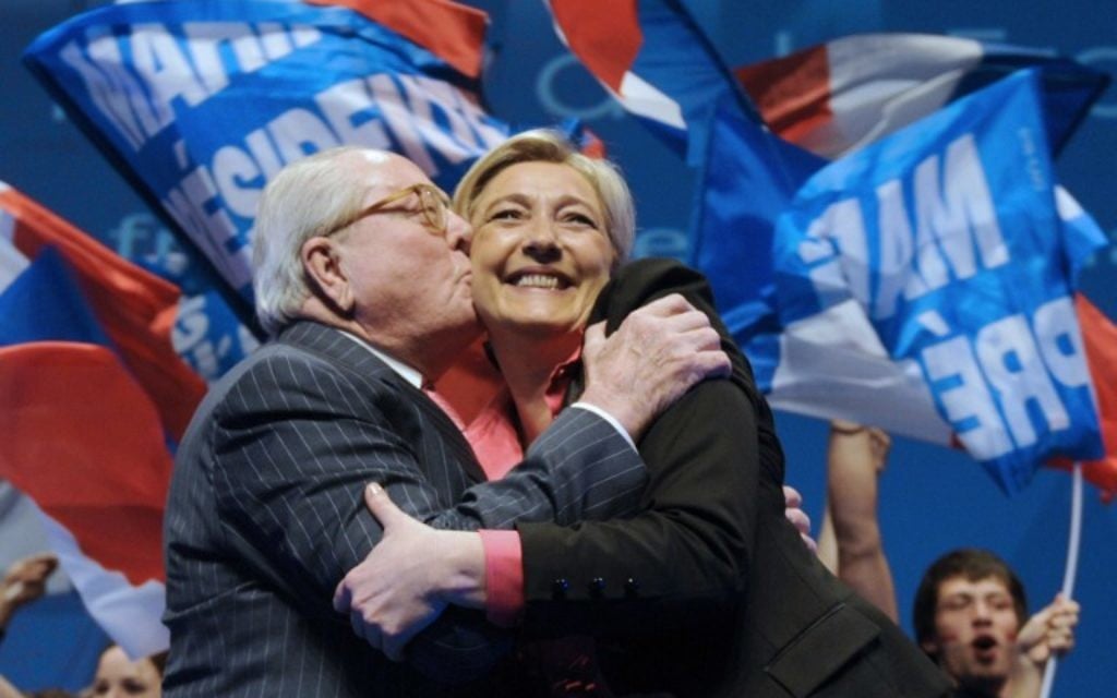 Ce fichier photo pris le 30 mars 2012 montre Marine Le Pen (d) embrassée par son père, président honoraire FN, Jean-Marie Le Pen (g) à la fin d'une réunion de campagne à Nice, dans le sud-est de la France. (Crédit : AFP PHOTO / BORIS HORVAT)