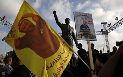 Des manifestants palestiniens brandissent des portraits de Marwan Barghouthi devant la statue de  Nelson Mandela pendant un rassemblement de soutien aux prisonniers en grève de la faim dans les prisons israéliennes, à Ramallah, en Cisjordanie, le 3 mai 2017. (Crédit : Abbas Momani/AFP)
