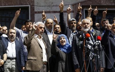 Ismail Haniyeh, chef du groupe terroriste du Hamas, annonçant l'arrestation du tueur présumé de Mazen Foqaha, abattu le 24 mars 2017, près de sa maison dans la ville de Gaza, aux côtés de l'épouse de Foqaha et de Yahya Sinwar, chef du Hamas à Gaza, le 11 mai 2017. (Crédit : Mohammed Abed/AFP) Ismail Haniyeh, chef du groupe terroriste du Hamas, annonçant l'arrestation du tueur présumé de Mazen Foqaha, abattu le 24 mars 2017, près de sa maison dans la ville de Gaza, aux côtés de l'épouse de Foqaha et de Yahya Sinwar, chef du Hamas à Gaza, le 11 mai 2017. (Crédit : Mohammed Abed/AFP)