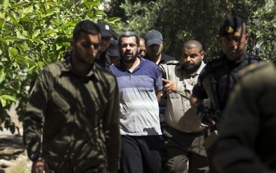 Hisham al-Aloul, au centre, 44 ans, jugé coupable de complicité de l'assassinat de Mazen Foqaha, escorté par les forces du Hamas devant la cour militaire de Gaza, le 21 mai 2017. (Crédit : Mahmud Hams/AFP) Hisham al-Aloul, au centre, 44 ans, jugé coupable de complicité de l'assassinat de Mazen Foqaha, escorté par les forces du Hamas devant la cour militaire de Gaza, le 21 mai 2017. (Crédit : Mahmud Hams/AFP)
