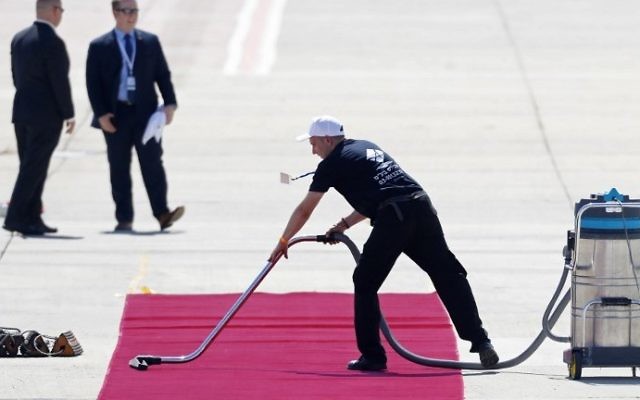 Un employé aspire le tapis rouge que fouleront le président américain Donald Trump et sa femme Melania Trump à l'aéroport international de Ben Gurion, le 22 mai 2017. (Crédit : AFP Photo /Jack Guez)