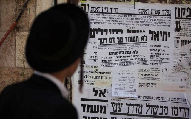 Un Juif ultra-orthodoxe lit une affiche appelant à la libération d'un membre de la secte juive anti-sioniste Neturei Karta, le 1er août 2013. Illustration. (Crédit : Yonatan Sindel/Flash90)