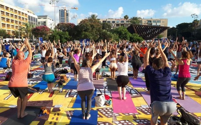 Des centaines de personnes sur la plus grande installation artistique en tapis de yoga au monde, illustrée par Amit Trainin pour représenter Israël en 2018, à l'occasion de la 3e Journée internationale du Yoga à Tel Aviv, le 21 juin 2017. (Crédit : Guy Mador/skylens) Des centaines de personnes sur la plus grande installation artistique en tapis de yoga au monde, illustrée par Amit Trainin pour représenter Israël en 2018, à l'occasion de la 3e Journée internationale du Yoga à Tel Aviv, le 21 juin 2017. (Crédit : Guy Mador/skylens)