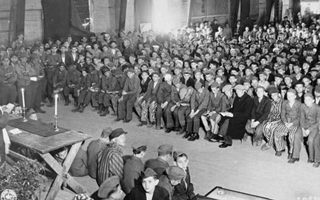 Le rabbin Herschel Schachter menant des services pour les survivants de l'Holocauste lors de la fête juive de Shavuot, dans le camp de concentration de Buchenwald, le 16 mai 1945 (Crédit : Wikimedia Commons)