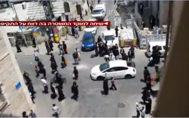 Des hommes ultra-orthodoxes s'en prennent à un soldat en uniforme, dans le quartier de Mea Shearim à Jérusalem, le 9 juin 2017. (Crédit : capture d'écran la Deuxième chaîne)
