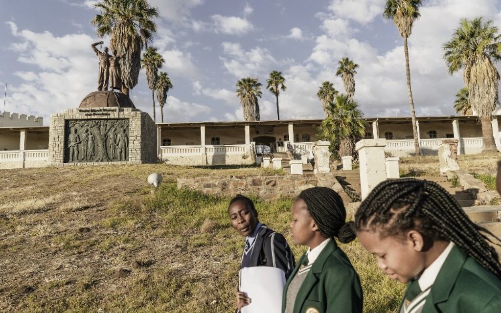 Des écolières namibiennes passent devant le mémorial construit en hommage aux victimes du prétendu génocide commis par les forces allemandes des tribus Herero et Nama en 1904, le 20 juin 2017 à Windhoek, en Namibie (Crédit : AFP PHOTO / GIANLUIGI GUERCIA)