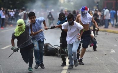 Les militants anti-gouvernementistes font glisser une moto de police brûlée après l'explosion d'un engin explosif lors d'une manifestation contre les élections d'une assemblée constituante à Caracas le 30 juillet 2017. (Crédit : AFP / Ronaldo SCHEMIDT)