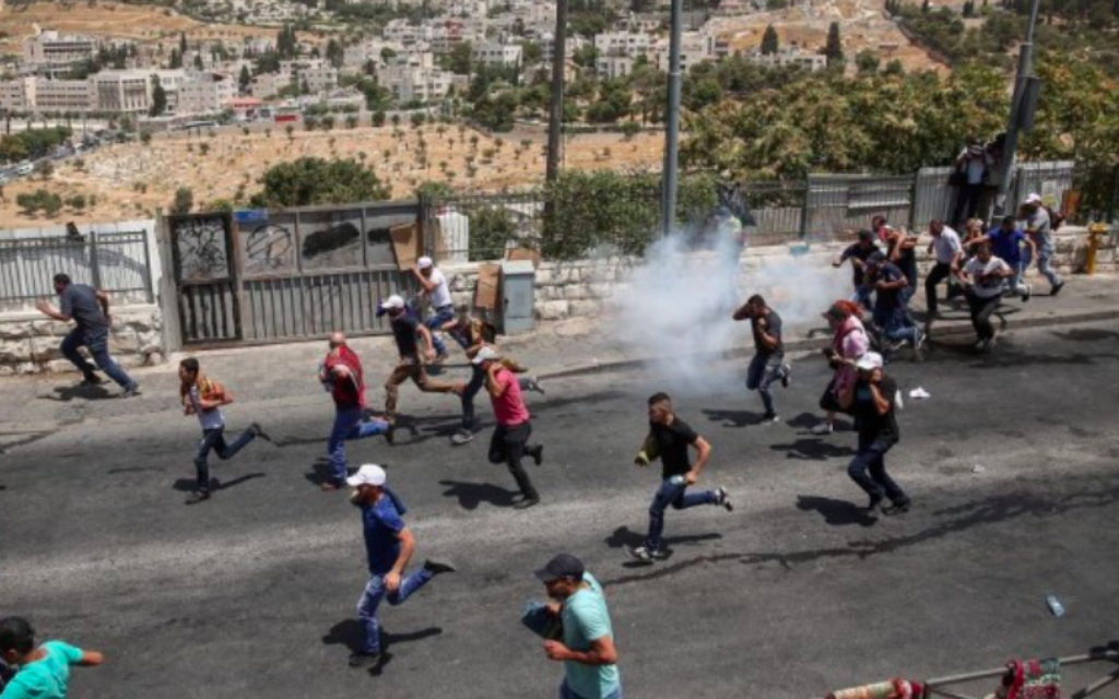 Des Palestiniens courent alors que la police israélienne émet des gaz lacrymogènes après les affrontements lors des prières du vendredi dans le quartier de Jérusalem-Est à Wadi al-Joz, le 28 juillet 2017 (Crédit : Miriam Alster / Flash90)