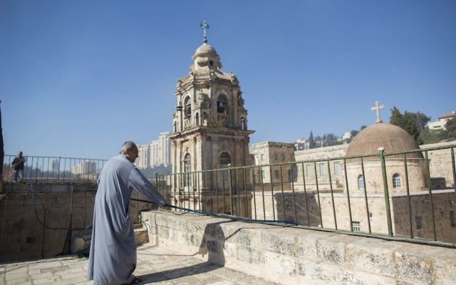 Un moine orthodoxe du monastère de la Croix avec un tuyau, alors qu'il se tient sur le toit du monastère pendant un incendie survenu dans la "Vallée de la croix", dans le centre de Jérusalem, le 2 juillet 2013 (Crédit : FLASH90)