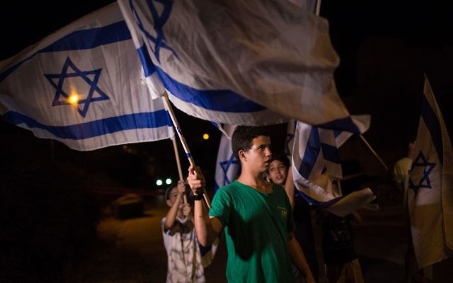 Des adolescents juifs israéliens brandissent des drapeaux israéliens aux abords de la maison de la famille Salomon dans l'implantation juive de Halamish dans le nord de la Cisjordanie le 220 juillet 2017 (Crédit : Hadas Parush/FLASH90) Des adolescents juifs israéliens brandissent des drapeaux israéliens aux abords de la maison de la famille Salomon dans l'implantation juive de Halamish dans le nord de la Cisjordanie le 220 juillet 2017 (Crédit : Hadas Parush/FLASH90)