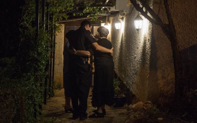 Un policier réconforte une femme qui vit à proximité de l'habitation où trois Israéliens ont été tués dans un attentat terroriste à l'arme blanche un jour plus tôt, dans l'implantation de Halamish, en Cisjordanie, le 22 juillet 2017 (Crédit : Hadas Parush/FLASH90) Un policier réconforte une femme qui vit à proximité de l'habitation où trois Israéliens ont été tués dans un attentat terroriste à l'arme blanche un jour plus tôt, dans l'implantation de Halamish, en Cisjordanie, le 22 juillet 2017 (Crédit : Hadas Parush/FLASH90)
