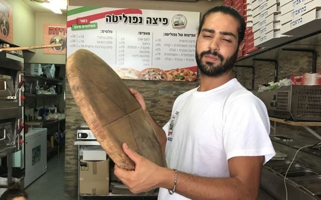 Shlomi Madar avec un plateau à pizza en bois, similaire à celui qu'il a employé pour neutraliser un terroriste palestinien qui a tenté de le poignarder dans sa pizzeria, à Petah Tikva, le 24 juillet 2017. (Crédit : Jacob Magid) Shlomi Madar avec un plateau à pizza en bois, similaire à celui qu'il a employé pour neutraliser un terroriste palestinien qui a tenté de le poignarder dans sa pizzeria, à Petah Tikva, le 24 juillet 2017. (Crédit : Jacob Magid)