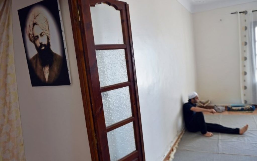 Un membre de la petite communauté ahmadie d'Algérie avec une photographie de Mirza Ghulam Ahmad, le fondateur du mouvement, dans une maison de Tilpasi, le 30 juin 2017. (Crédit : Ryad Kramdi/AFP)