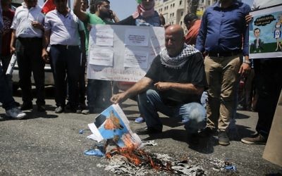 Un Palestinien brûlant un drapeau à l'effigie du président Donald Trump pendant une manifestation contre la visite d'une délégation américaine dirigée par Jared Kushner, à Ramallah, le 24 août 2017. (Crédit : Abbas Momani/AFP)