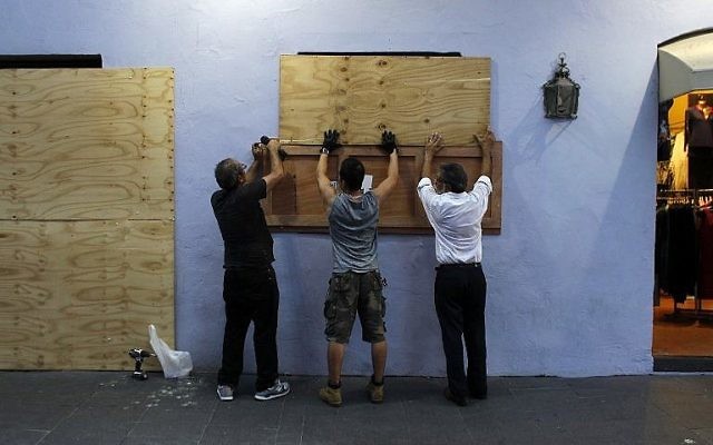 Des membres de la congrégation posent des panneaux en bois sur les fenêtres d'un commerce en préparation de l'arrivée de l'ouragan Maria à San Juan, à  Puerto Rico, le 18 sepptembre 2017 (Crédit :  AFP PHOTO/Ricardo ARDUENGO)