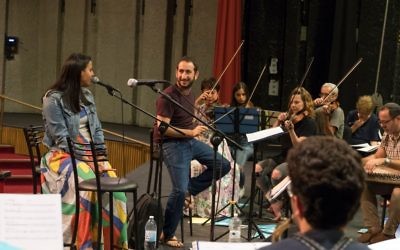 Le chef d'orchestre de l'Orchestre de Jérusalem Est-Ouest,   Tom Cohen, et la chanteuse  Nasreen Qadri, alors d'une répétition du concert 'Kulna' à Jérusalem (Crédit : Gil Rouvio/Mekudeshet)