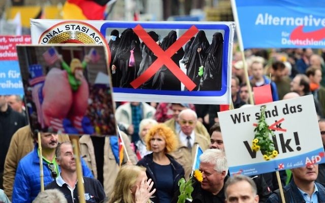 Un partisan du parti populiste de droite de l'Alternative pour l'Allemagne (AfD) porte une pancarte montrant des femmes en niqab barrées d'une croix durant une manifestation contre la politique d'asile du gouvernement allemand pendant une manifestation organisée par l'AfD à Berlin, le 7 novembre 2015 (Crédit : AFP PHOTO / JOHN MACDOUGALL) Un partisan du parti populiste de droite de l'Alternative pour l'Allemagne (AfD) porte une pancarte montrant des femmes en niqab barrées d'une croix durant une manifestation contre la politique d'asile du gouvernement allemand pendant une manifestation organisée par l'AfD à Berlin, le 7 novembre 2015 (Crédit : AFP PHOTO / JOHN MACDOUGALL)