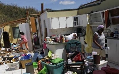 Les membres d'une famille collectent leurs affaires après la destruction par l'ouragan de leur maison à Toa Baja, à l'ouest de San Juan, à Puerto Rico,le 24 septembre 2017 après le passage de l'ouragan Maria (Crédit : AFP PHOTO / Ricardo ARDUENGO)