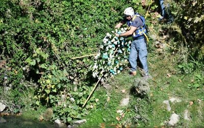La police récupère une gerbe de fleurs du club de football de la Lazio de Rome sur les rives du Tibre, après sa disparition du mur d'une synagogue de Rome pendant la nuit, le 25 octobre 2017. (Crédit : Alberto Pizzoli/AFP)